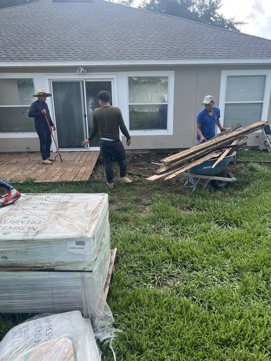 Old deck being removed with pallets of pavers delivered to the job site